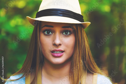 Portrait of a woman in the forest with a backpack and hat