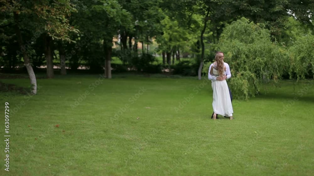 Happy man circling his wife on the hands in Park on green grass. Lovingcircling couple on a walk in the Park.