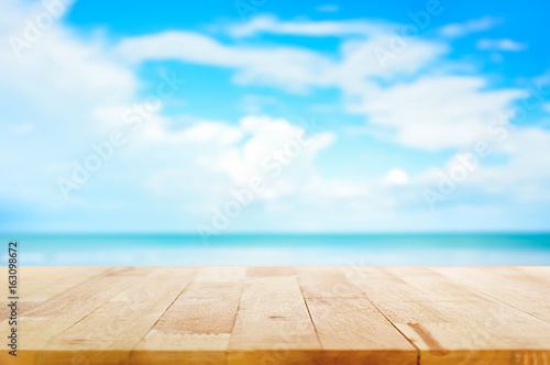 Wood table top on blur blue sea and sky background