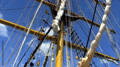 Masts, rigging, banners and flags on Indonesian tall ship Dewaruci against blue sky and clouds    photo