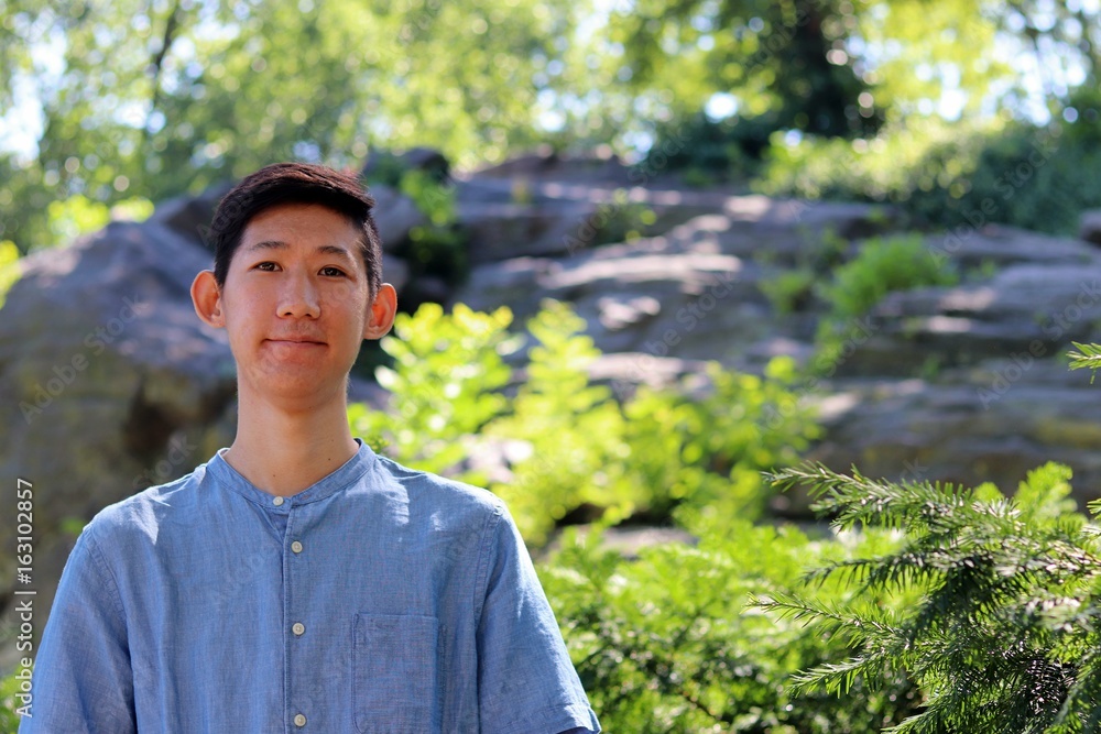 Young attractive asian american man standing next to scenic mountain forest background Young attractive asian american man standing next to scenic mountain forest background