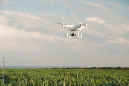White drone hovering in a bright blue sky. Drone copter flying with digital camera