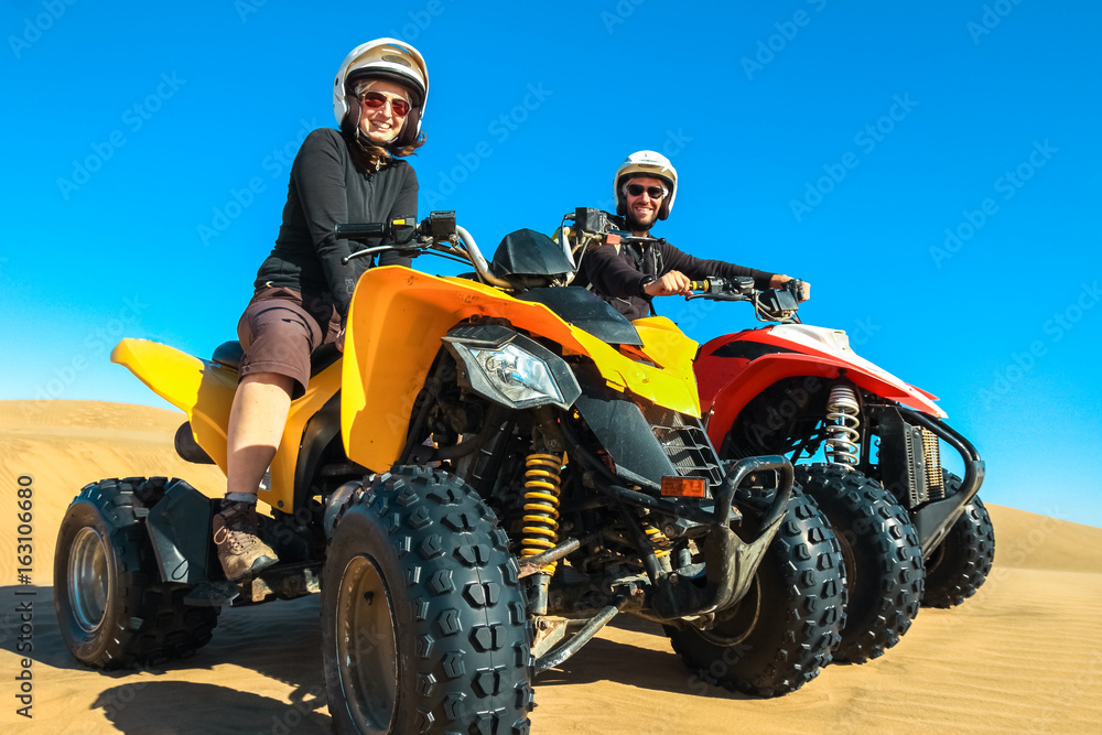 Quad driving people - happy smiling couple bikers in sand desert.