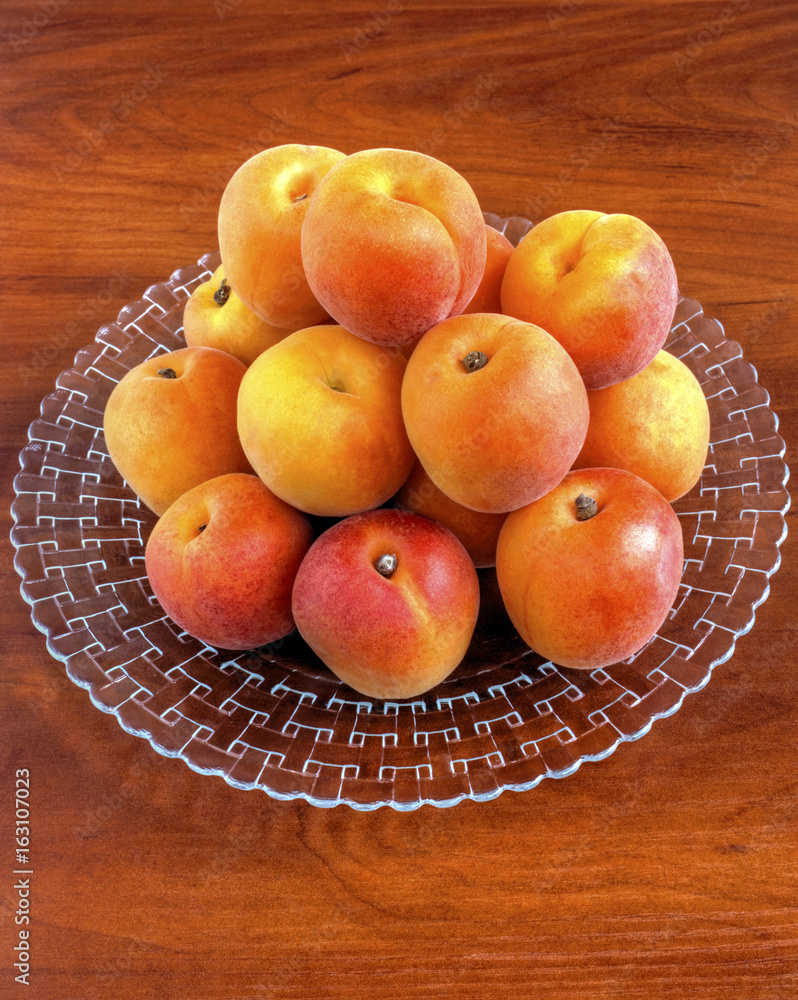 Fresh ripe apricots on plate on wooden background closeup Fresh ripe apricots on plate on wooden background closeup