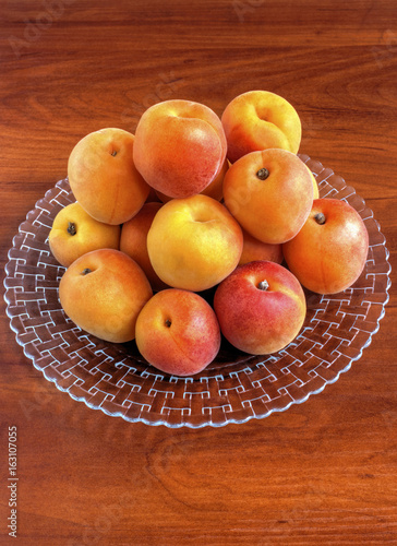 Fresh ripe apricots on plate on wooden background closeup