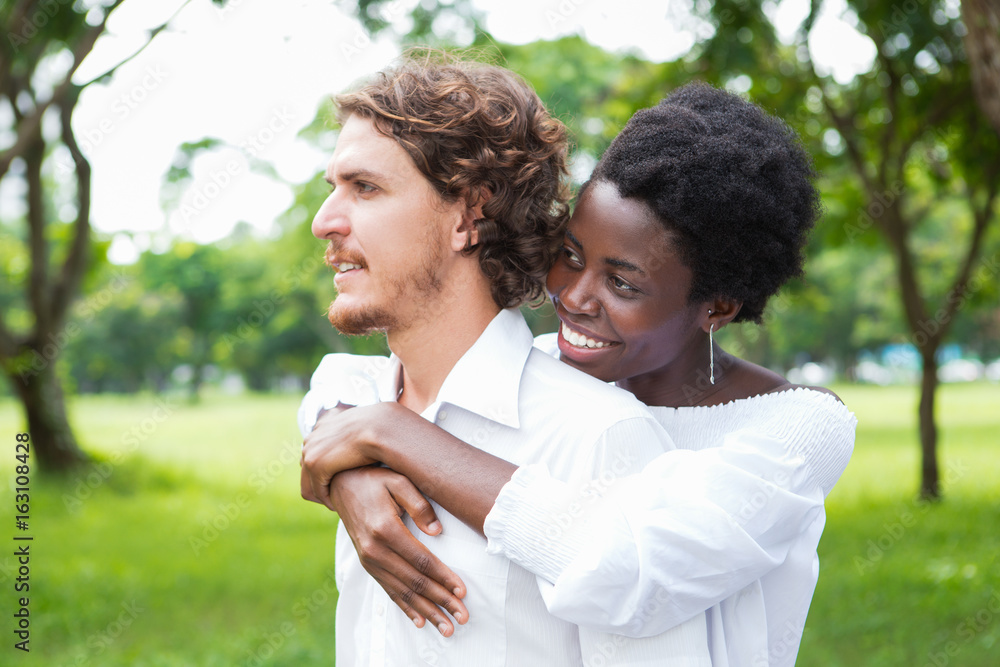 Happy young woman embracing her boyfriend in park Happy young woman embracing her boyfriend in park