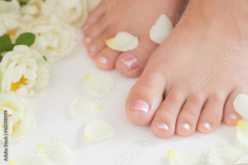 Young woman s feet. Smooth skin. Spring and summer atmosphere with fresh and fragrant white roses.