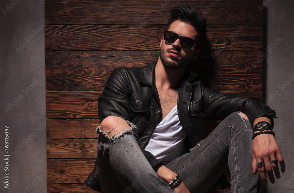 relaxed fashion man in sunglasses and leather jacket is sitting relaxed fashion man in sunglasses and leather jacket is sitting