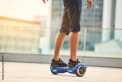 Legs of guy riding hoverboard. Person on blue gyroscooter. photo