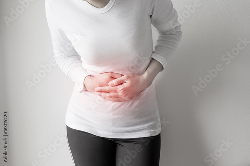 Woman stomachache on gray wall background. photo