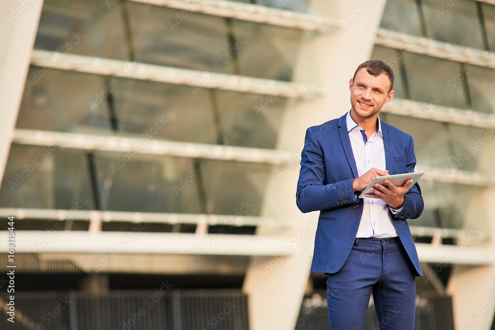 Young businessman with tablet smiling. Happy guy in a suit. Young businessman with tablet smiling. Happy guy in a suit.