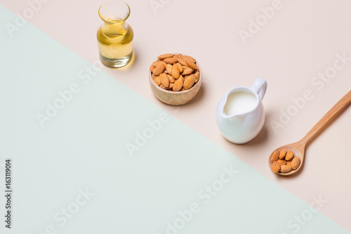 Almond oil in bottle and milk with almonds on light background.
