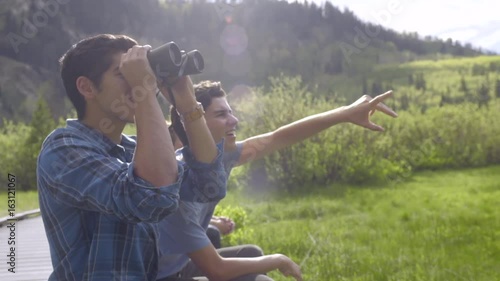 Teenage Boys Sit On A Boardwalk And Use Binoculars To Spot Wildlife (Slow Motion) photo