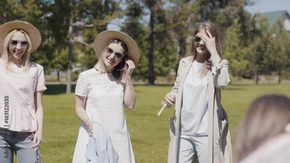 Three beautiful young women in sunglasses embrace, have fun and are photographed against the backdrop of greenery in a summer park. Girlfriends walk and spend time together in the park. Three beautiful young women in sunglasses embrace, have fun and are photographed against the backdrop of greenery in a summer park. Girlfriends walk and spend time together in the park.