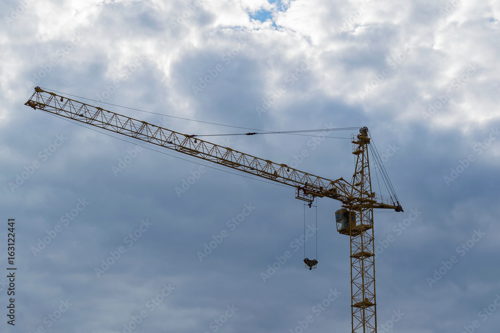 Yellow tower hydraulic crane that builds on a background of dark blue sky. Mock up. Ready for advertising
