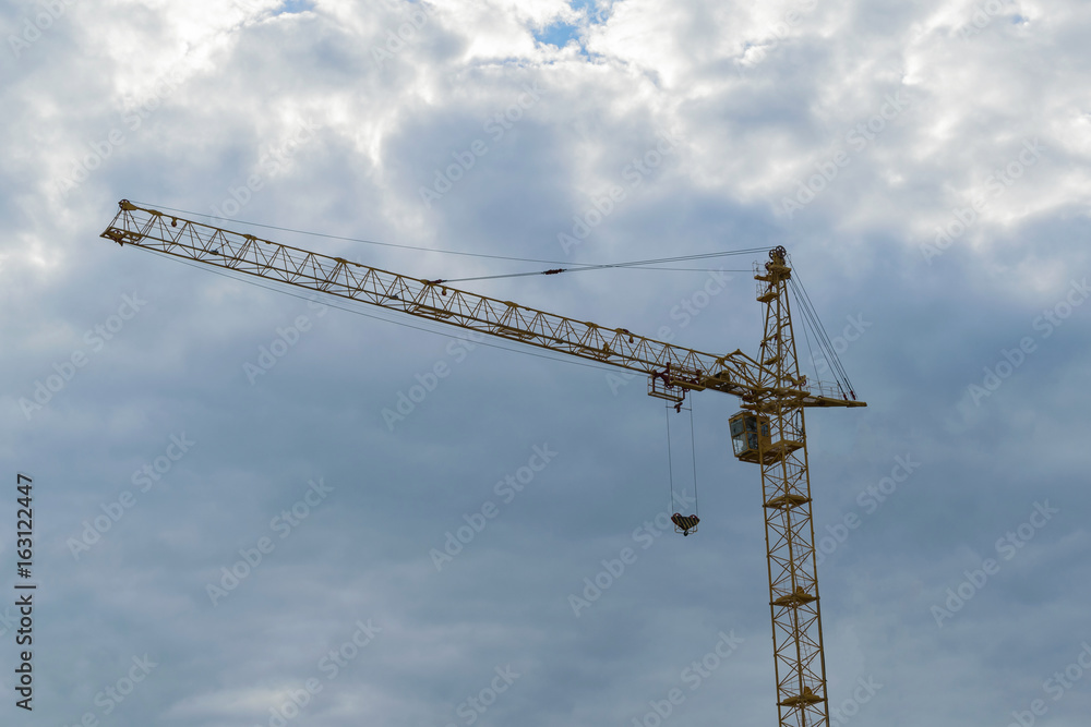 Yellow tower hydraulic crane that builds on a background of dark blue sky. Mock up. Ready for advertising Yellow tower hydraulic crane that builds on a background of dark blue sky. Mock up. Ready for advertising