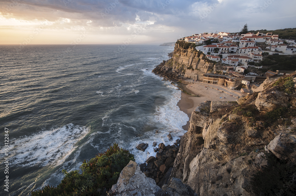 City caved in the rock in Azenhas do Mar beach, Portugal during te sunset
