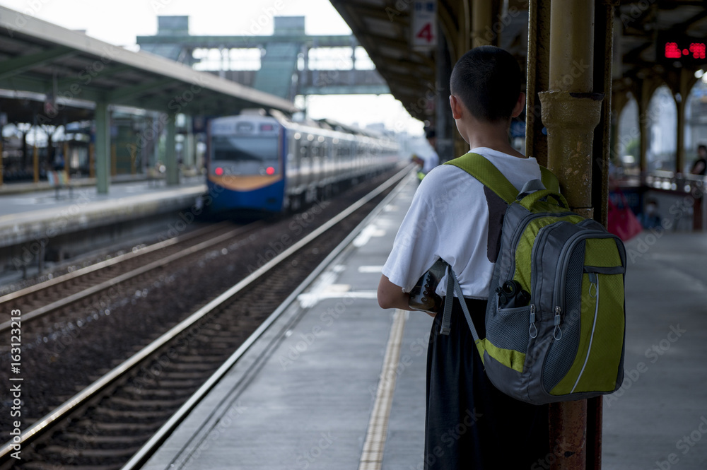 An Asian young man carrying a backpack on the platform and so on.