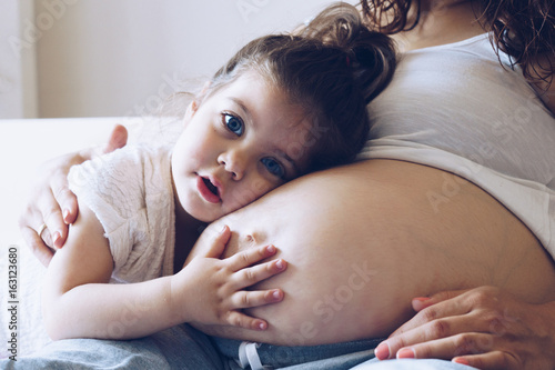 Vászonkép Happy kid girl hugging pregnant mother's belly