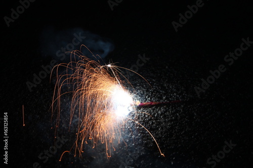 A child playing with burning sparkler firework. Motion blur effect over black background. Selected Focus. Light trail photo