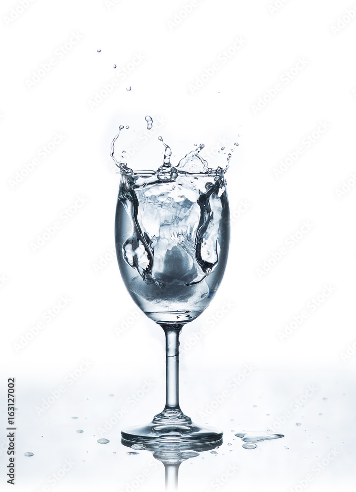 Water splash with ice in glass on white Water splash with ice in glass on white