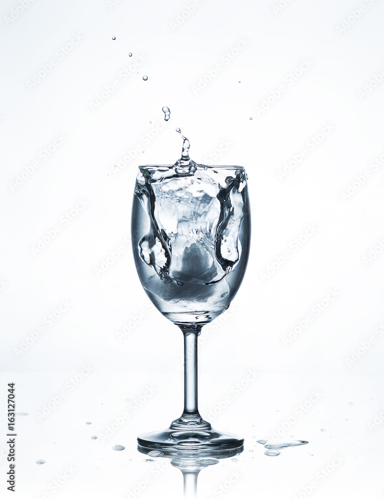 Water splash with ice in glass on white Water splash with ice in glass on white