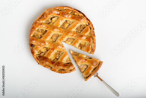 Whole apple pie, top view, a piece is taken out with a chrome cake server photo