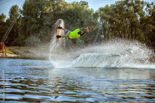 Wakeboarder young athlete, he jumped over the water creating a splash.