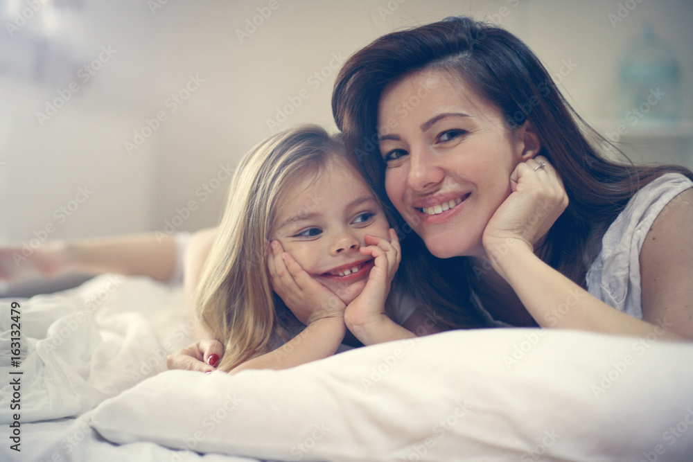 Mother with her cute little daughter lying on bed. Mother with her cute little daughter lying on bed.