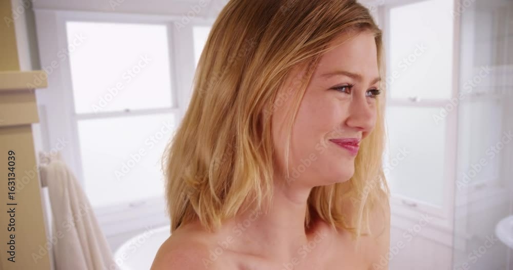 Fresh fun laughing blonde woman with bare shoulders smiling in bathroom Fresh fun laughing blonde woman with bare shoulders smiling in bathroom