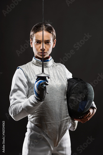 Tableau sur toile Young woman fencer in white fencing costume