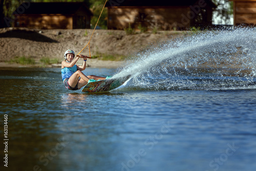 Fototapeta Naklejka Na Ścianę i Meble -  Waking on wakeboarding summer sport, a woman trains.