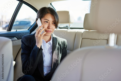 Business woman in suit talking by the phone in the car