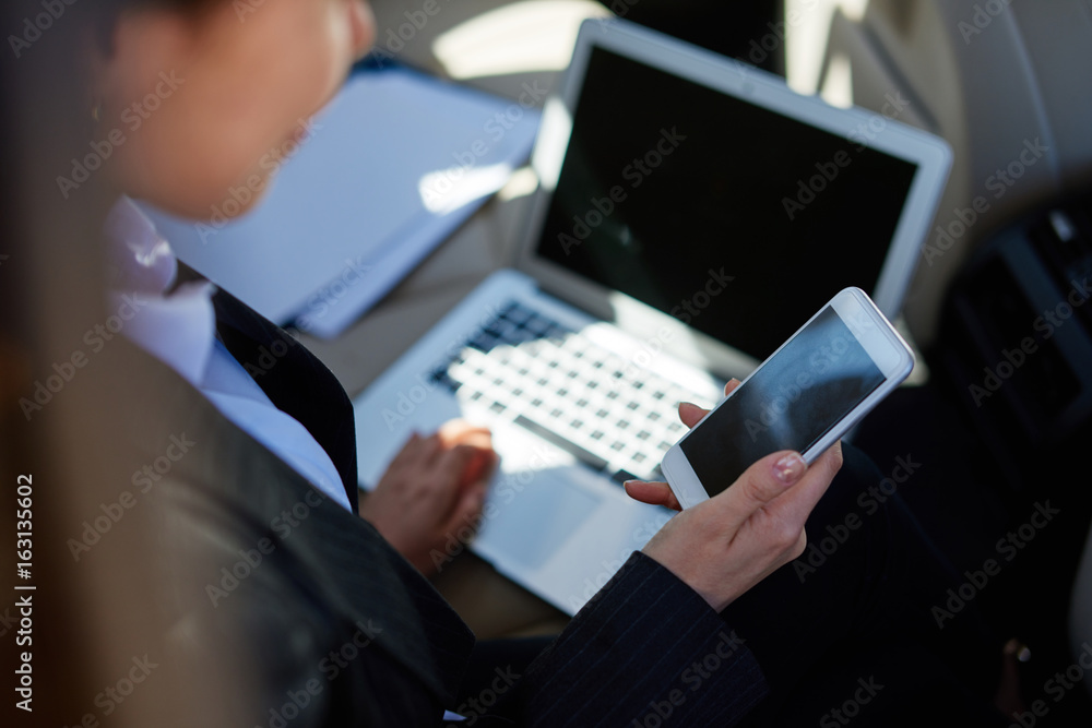 Busy woman in suit sitting in car and writing message Busy woman in suit sitting in car and writing message
