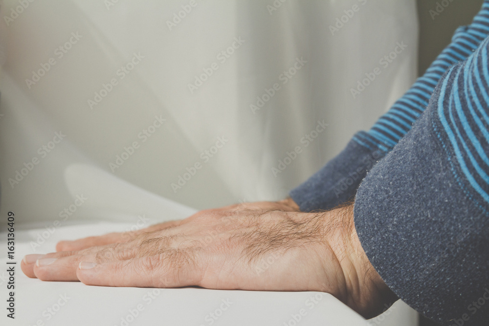 Naklejka premium Man leaning and puts his hands down on white cloth background