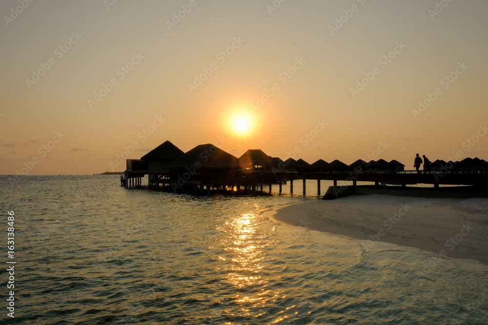 Sunset and water bungalows, abstract vacation background. Image has grain or blurry or noise and soft focus when view at full resolution. (Shallow DOF, slight motion blur)