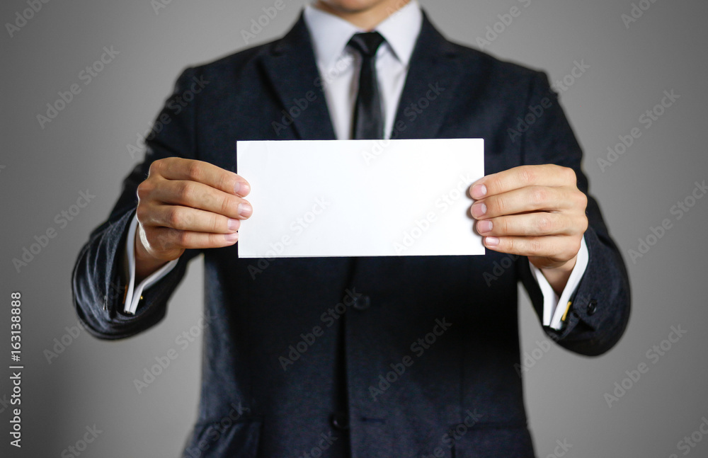 A man in black suit holding blank clear white of the sheet. Closeup. Isolated A man in black suit holding blank clear white of the sheet. Closeup. Isolated