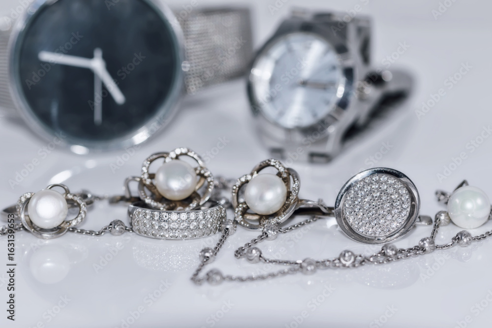 Silver earrings with pearl on the background of watches Silver earrings with pearl on the background of watches
