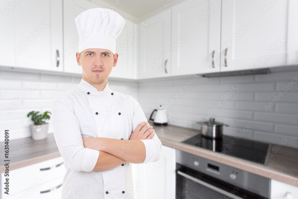 young chef man in uniform posing in modern kitchen young chef man in uniform posing in modern kitchen