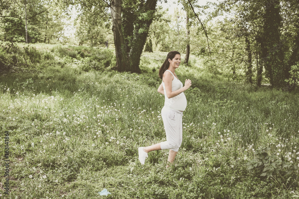 Pregnant  woman jogging in field.