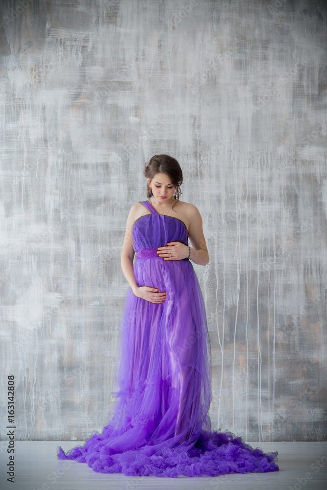 beautiful pregnant woman posing in purple dress in Studio beautiful pregnant woman posing in purple dress in Studio