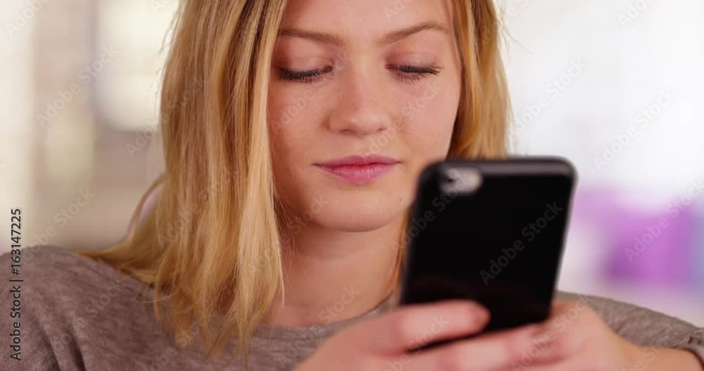 Pretty millennial girl using cellular phone to send text messages Pretty millennial girl using cellular phone to send text messages