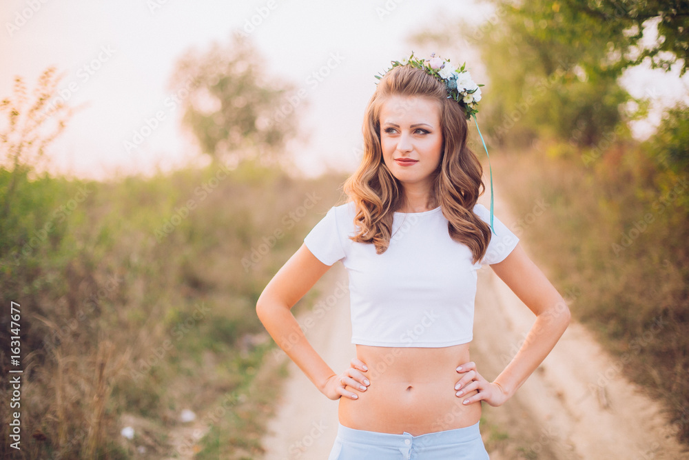 Romantic girl in a wreath of wild flowers in a field. Summer life. Beauty and sport Romantic girl in a wreath of wild flowers in a field. Summer life. Beauty and sport