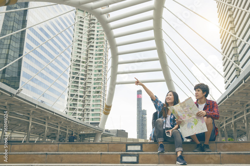 Young asian hipster and her boy friend on background of Thailand city . Look seaching direction map while traveling in city during vacation. © somchaikhun