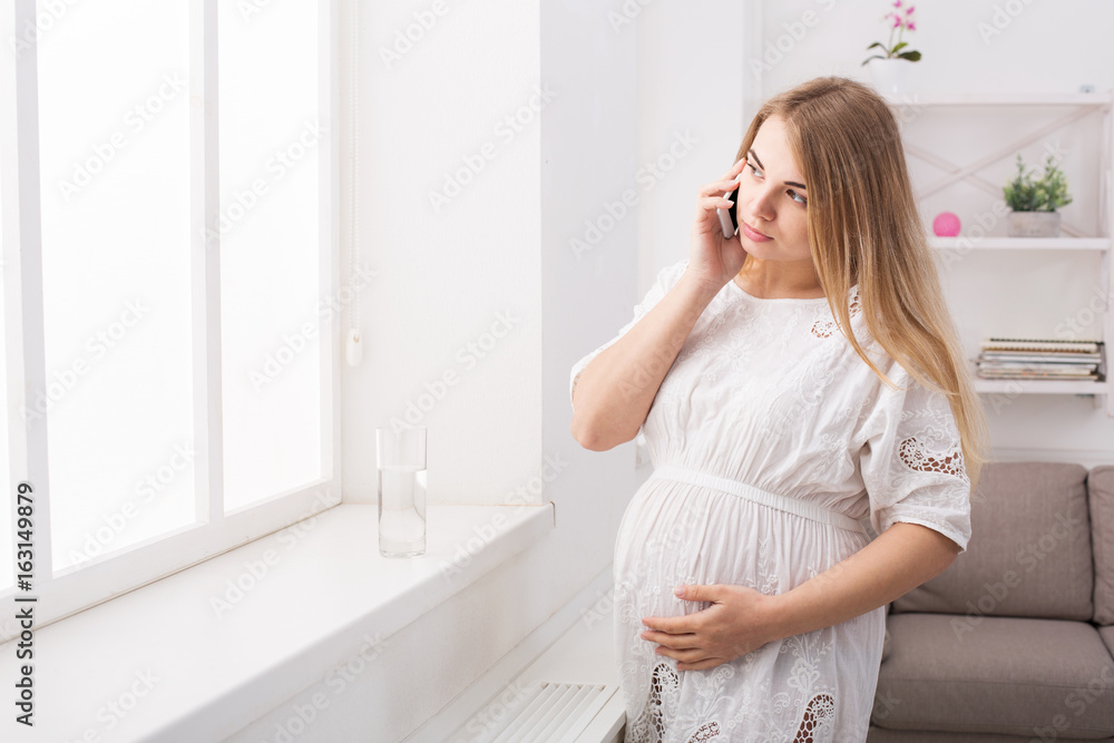 Young pregnant woman talking on her smartphone Young pregnant woman talking on her smartphone