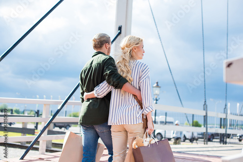 rear view of casual couple holding shopping bags while walking together on the bridge © LIGHTFIELD STUDIOS