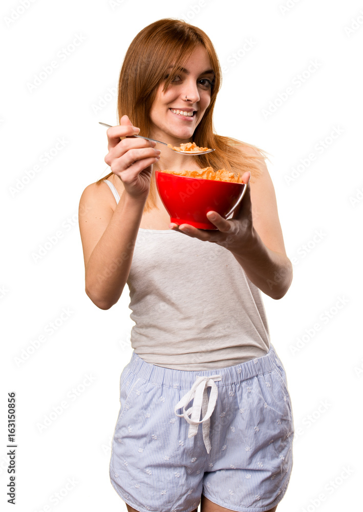 Beautiful girl in pajamas eating cereals from a bowl Beautiful girl in pajamas eating cereals from a bowl