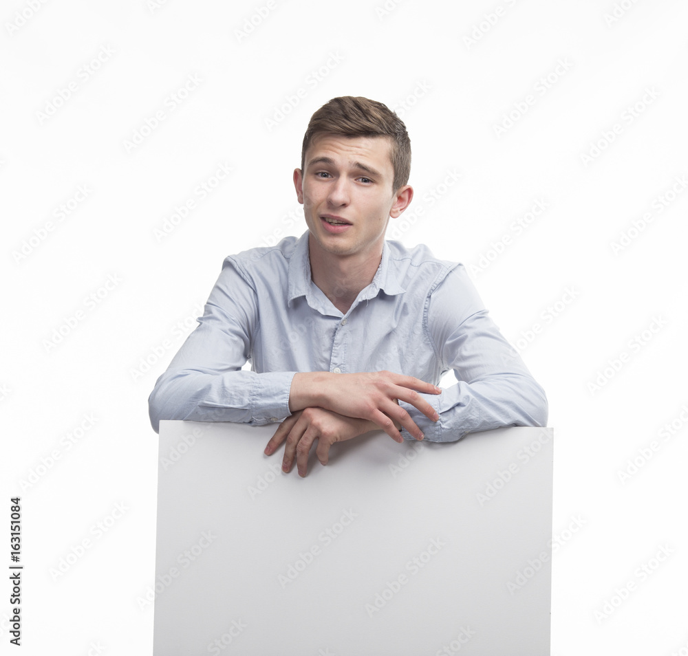 Young surprised man portrait of a confident businessman showing presentation, pointing paper placard gray background. Ideal for banners, registration forms, presentation, landings, presenting concept. Young surprised man portrait of a confident businessman showing presentation, pointing paper placard gray background. Ideal for banners, registration forms, presentation, landings, presenting concept.