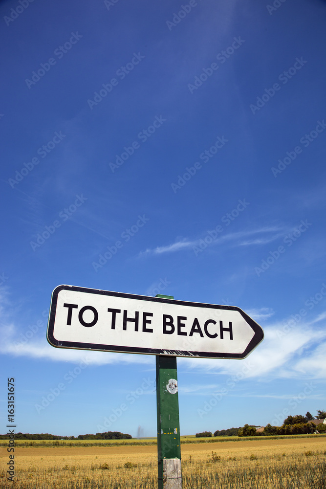 In the countryside a road sign with the inscription to the beach.
