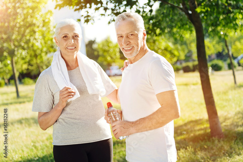 Positive aged couple preparing for sport exercises in the park